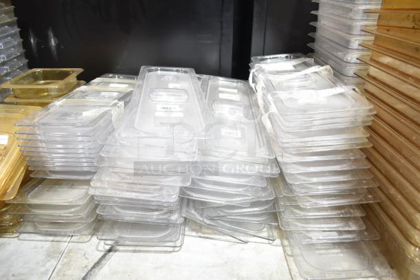 Lot of various clear and amber drop-in bins and lids stacked together, some with visible barcodes, in used condition.