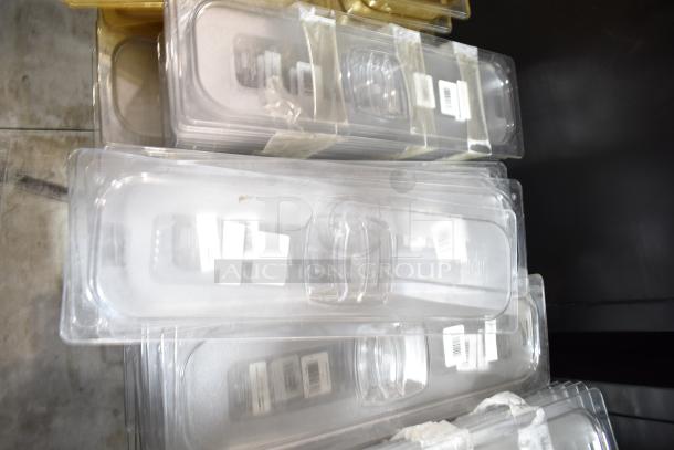 Lot of clear plastic drop-in bins and lids, stacked, with visible barcode labels. Generally good condition.