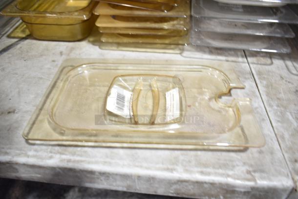 Lot of various plastic drop-in bins and lids, stacked on a metal surface. Some lids show visible wear. Barcodes are present.