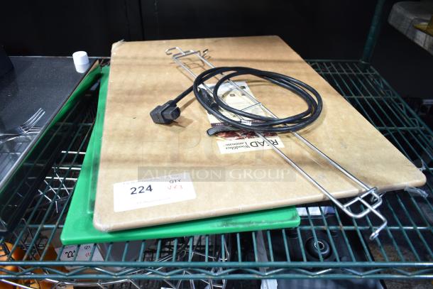 Three items including a large wooden cutting board, a green cutting board, and a black cable, on a metal shelf. Auction tag reads "224 JX3".