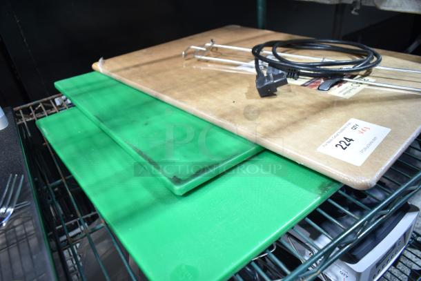 Three cutting boards, two green plastic and one wooden with attached electrical cord, on metal shelves. Auction sticker visible.