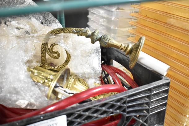 Lot of various items including red hoses and brass candle holders, bubble-wrapped in a black crate.