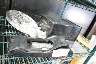 Auction item lot including various kitchen utensils, perforated steel basket, slicer, and 3-tined forks on metal shelving.