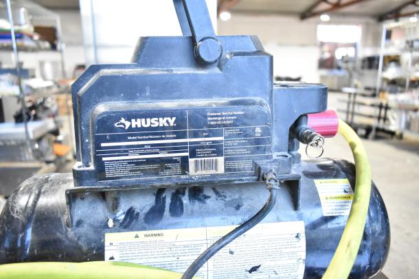 2016 Husky 0100211A Air Compressor by ServIt, black, model plate visible, slight wear, includes yellow hose.