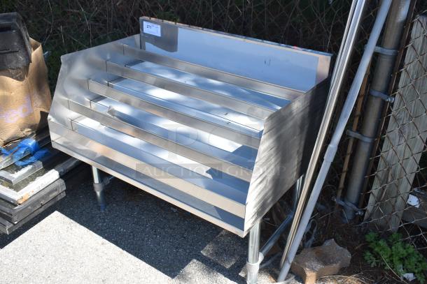 Brand new commercial bottle display rack, stainless steel, scratch and dent condition, multiple tiers, ideal for retail.