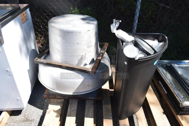 Rooftop mushroom exhaust fan and black poly trash can on wooden pallets; fan in used condition, trash can filled with materials.