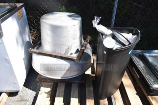 Rooftop mushroom exhaust fan and black poly trash can on wooden pallets; fan in used condition, trash can filled with materials.