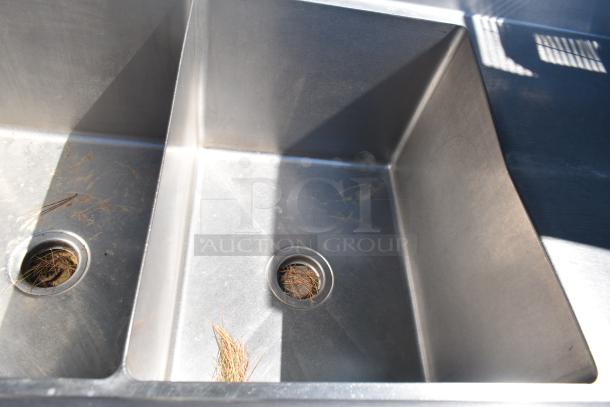 Duke Commercial 3 Bay Sink with dual drain boards, stainless steel, slight debris present, ideal for heavy-duty use.