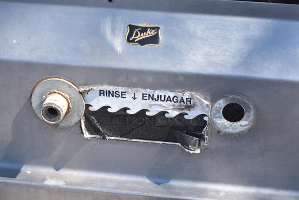 Duke Commercial 3 Bay Sink with dual drain boards, stainless steel, featuring rinse label and Duke emblem. Rugged condition.