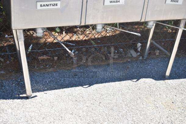 Commercial 3 bay sink with dual drain boards, labeled "Sanitize," "Wash," and "Rinse," stainless steel, outdoor setting.