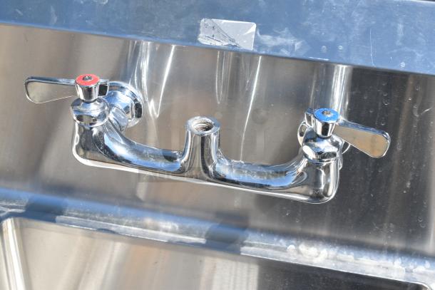 Commercial 3 bay sink with dual drain boards, polished chrome faucets, indicating hot and cold water. Clean and functional.