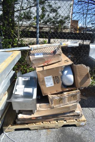 Pile of brand new scratch and dent items, including boxed Zurn toilet bowl and stainless steel toast chute, on pallet.