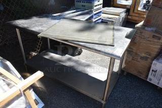 Commercial metal table with lower shelf, weathered surface, caster wheels, ideal for kitchen use, shows signs of use.