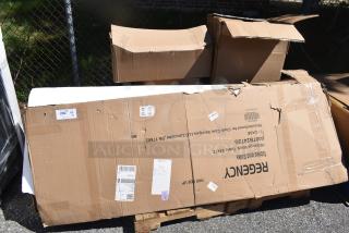 Boxes containing scratch and dent items, including Regency Work Table. Labels show model and handling instructions.