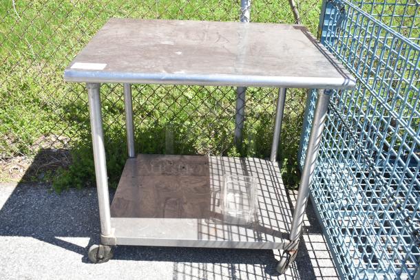 Commercial stainless steel table with under shelf, on heavy-duty casters. Good condition, ideal for industrial use.