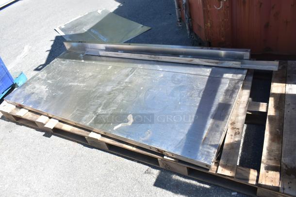 Three metal panels on a pallet, varying in size and finish. Suitable for industrial or DIY use. Light wear visible.