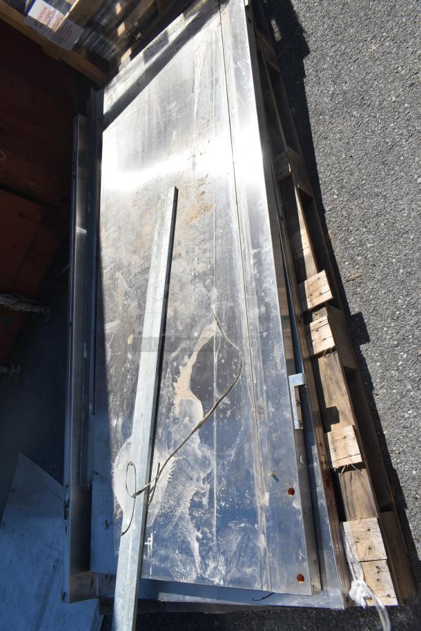 Three varied metal panels on a pallet, showing wear and slight rust. Features include mounting holes and a loose wire.