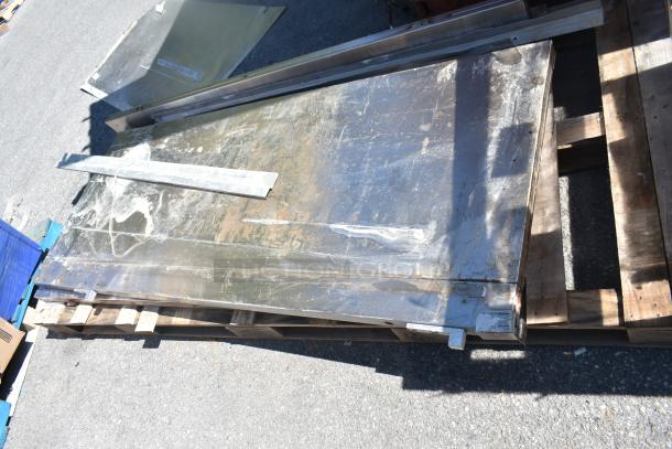 Three various metal panels with visible wear and scratches, stacked on a pallet, ideal for industrial use or projects.