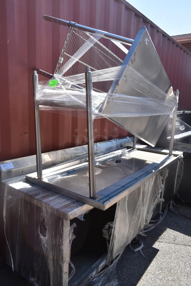 Stainless steel work counter with doors, wrapped in plastic. Includes two tables. Shows minor wear.