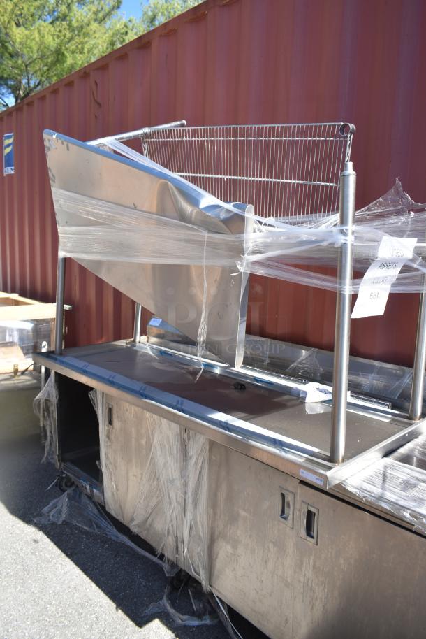 Three stainless steel items wrapped in plastic, including two tables and a work counter with doors, labeled "Used Assets, Club 651."