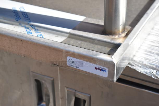 Stainless steel work counter with doors, includes label indicating "Winholt" and NSF certification. Good condition.