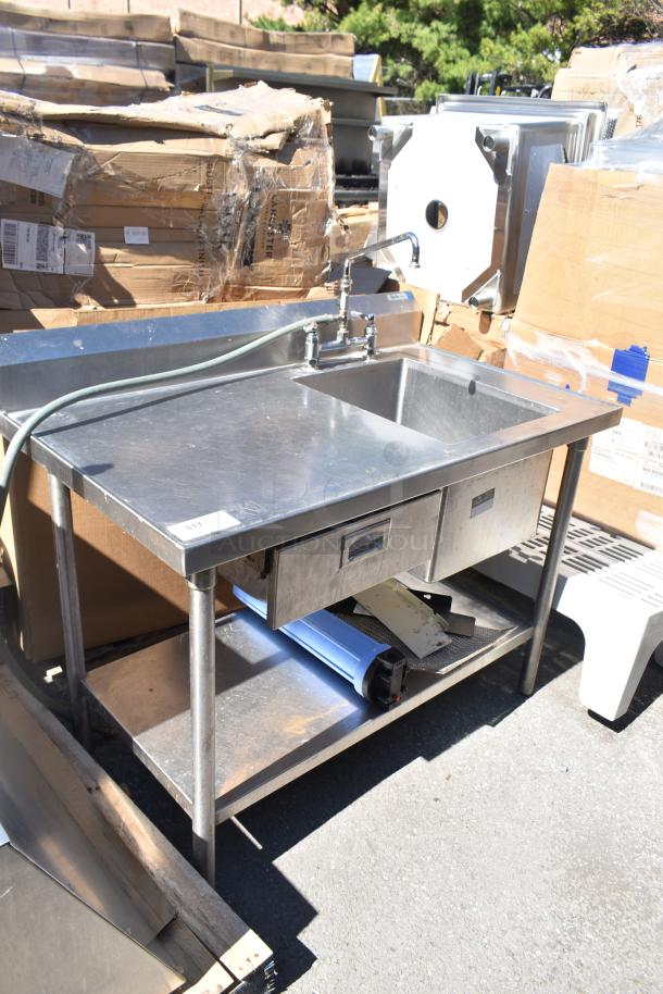 Commercial counter with sink bay, stainless steel finish, with faucet, storage drawer, and lower shelf. Good condition.