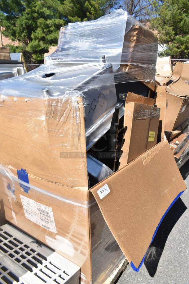 Cardboard boxes wrapped in plastic, containing brand new scratch and dent items. Visible labels indicate additional parts.