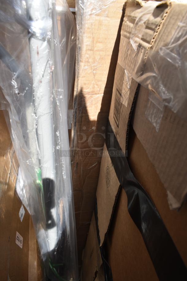 Cardboard boxes containing six new scratch and dent items, including a ban rack and mop sink, wrapped in plastic.