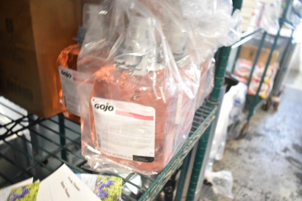 A tiered lot with GoJo Luxury Foam Handwash bottles in plastic packaging on a metal shelf.