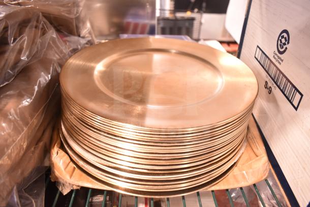Stack of gold plate chargers, lightly used, on a shelf. Includes pizza peels. 28 items total.