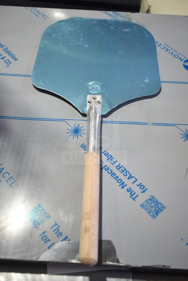 Pizza peel with wooden handle and metal blade, features visible logo, part of 28-item auction lot.