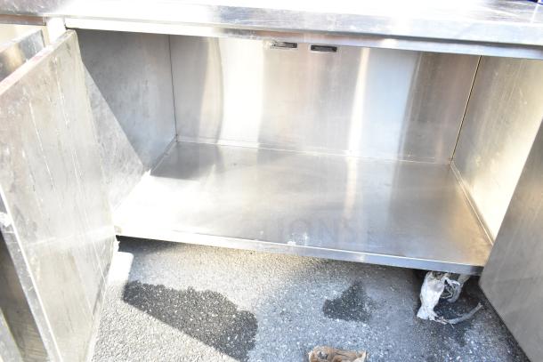 Commercial stainless steel counter with open doors and undershelf, used condition. Ideal for kitchen storage solutions.