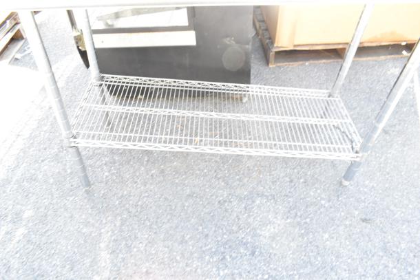 A commercial table with a wire under shelf, metal frame, used condition, ideal for storage and workspace organization.