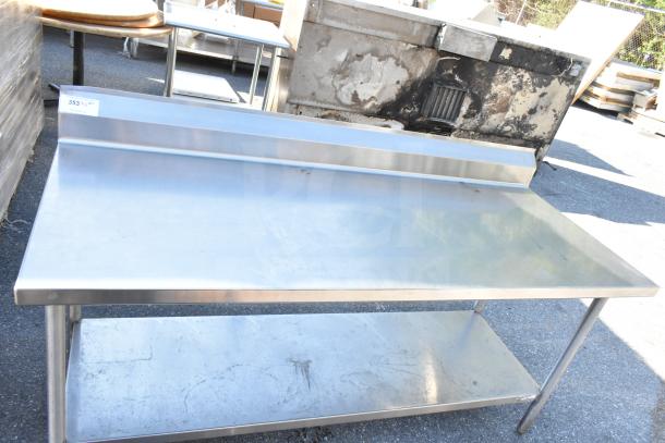 Stainless steel commercial table with under shelf and 6-inch backsplash, minor surface marks, sturdy condition.