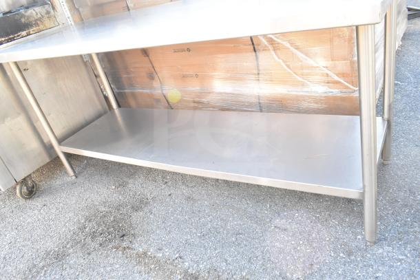 Commercial stainless steel table with under shelf, used condition, sturdy metal construction, ideal for kitchen or workshop.