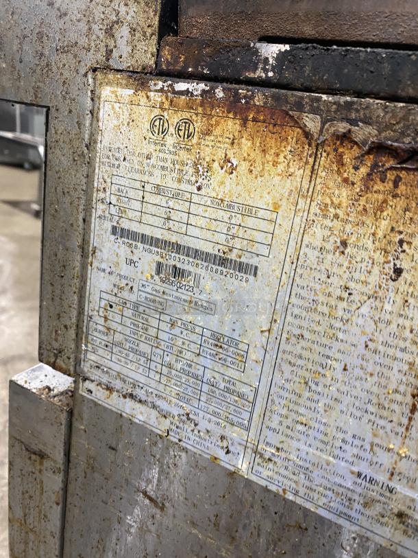 Migali C-RO6B-NG commercial stove label detail, showing model and serial number on weathered stainless steel surface.