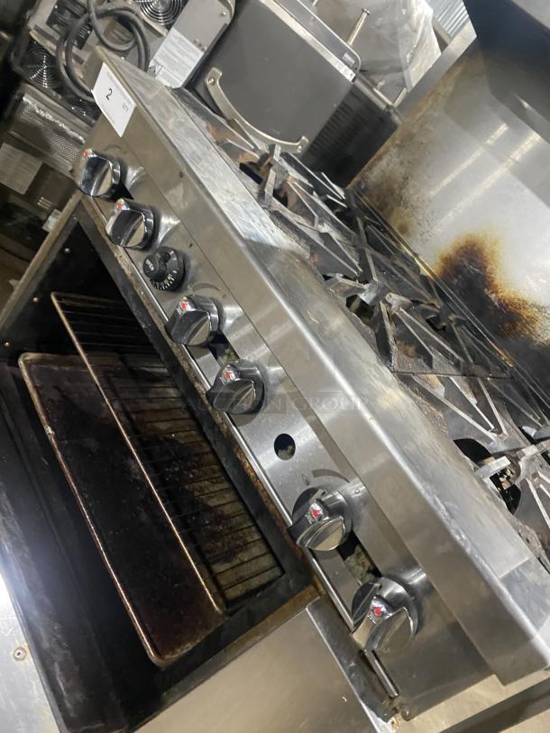 Migali 6 burner natural gas stove, Model CRO6B, stainless steel, raised backsplash, salamander shelf, oven below, on casters.