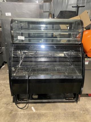 Commercial black dual service display case merchandiser with glass. Refrigerated unit, in used condition with visible wiring.