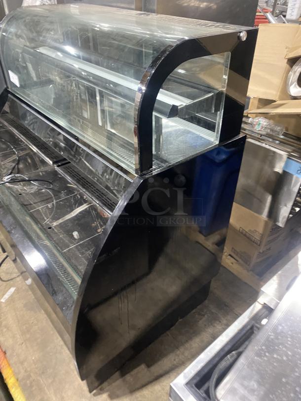 Commercial black dual service glass refrigerated display case, features curved glass and shelving, good condition.