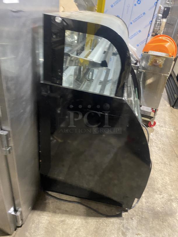 Commercial black dual service display case merchandiser, glass refrigerated, used condition, with curved glass front.
