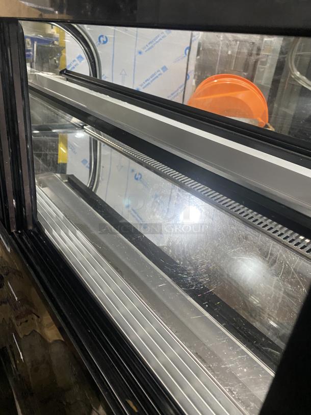 Commercial black dual service display case merchandiser, refrigerated glass, minor scratches, sleek design, ideal for businesses.