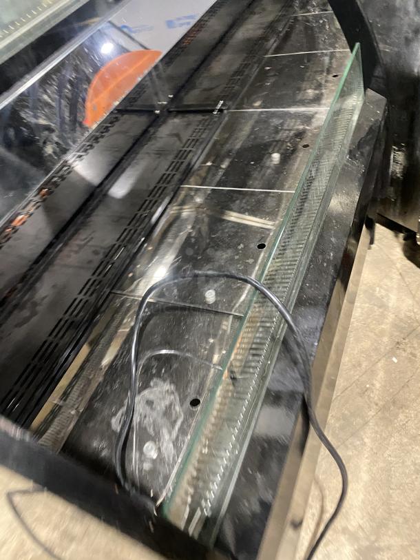 Commercial black dual service glass display case, refrigerated, showing interior shelves and wiring, fair condition.