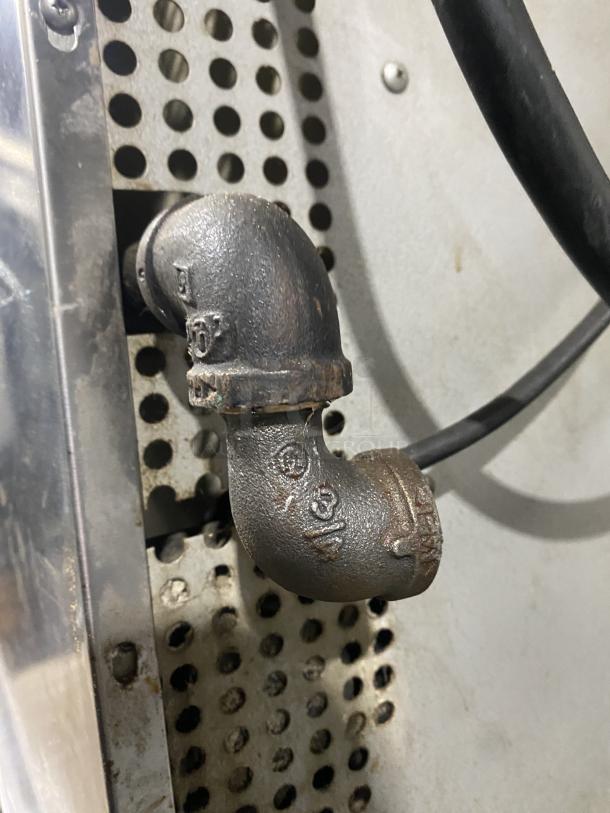 A metal pipe fitting attached to a perforated steel panel on a Southbend convection oven, showing wear.