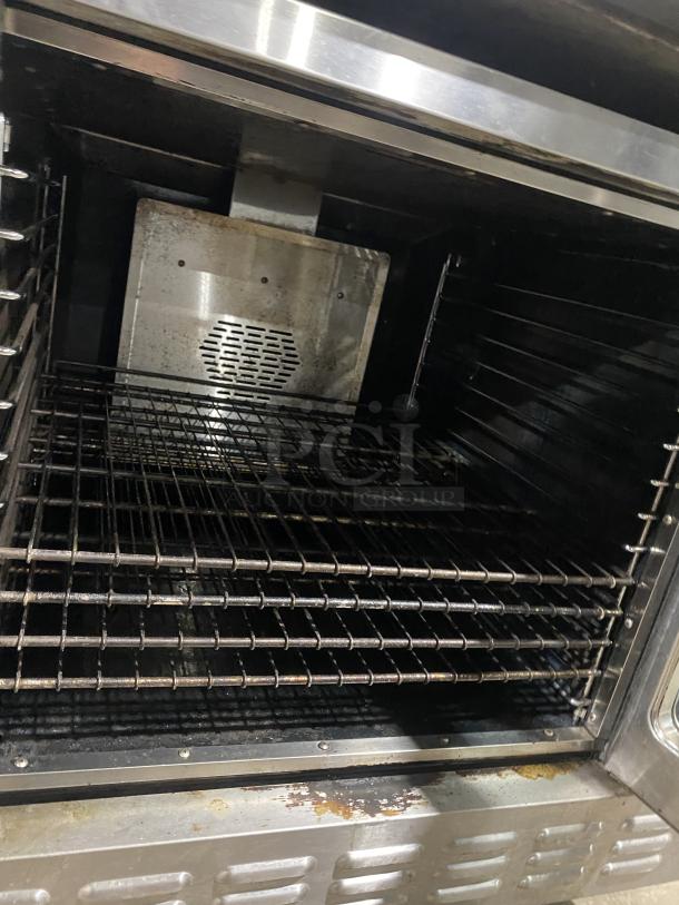 Majestic Series commercial stainless steel convection oven with wired racks, used; interior view showing oven racks and vent.