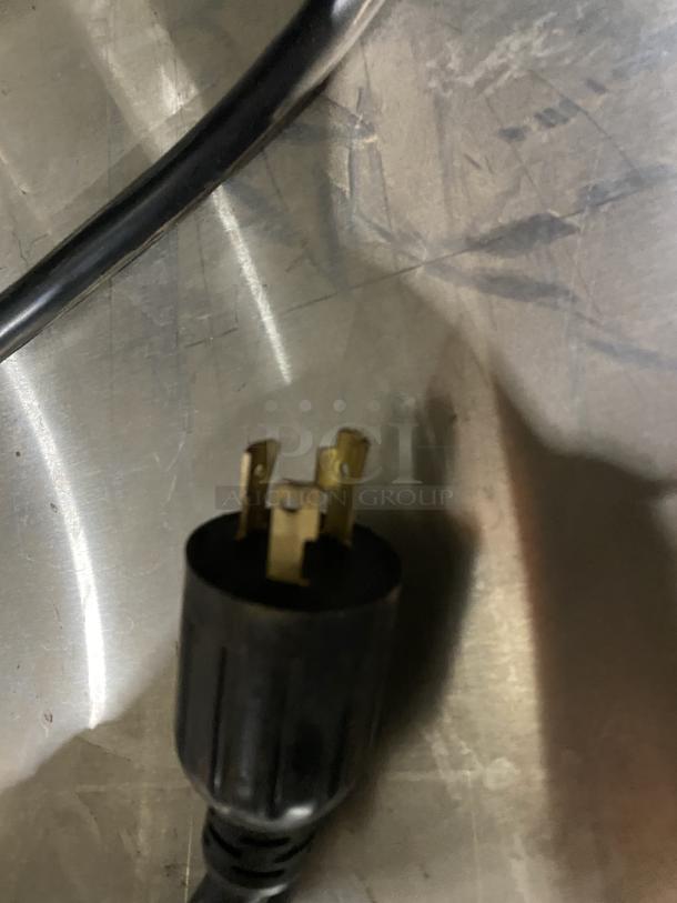 Close-up of a black electric plug for the Duke E305-25SS-SWM hot food table, showing three brass prongs.