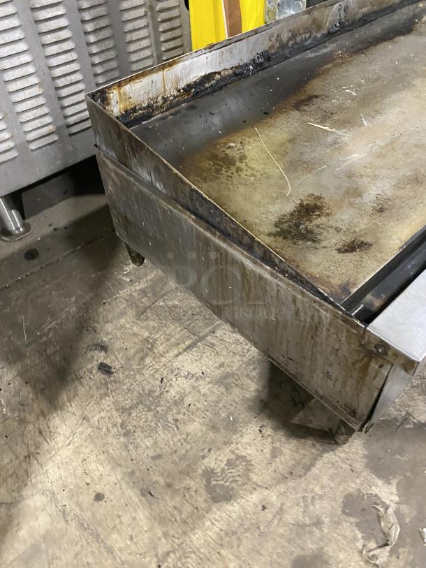 Garland stainless steel countertop griddle on legs, commercial use, shows signs of wear, sturdy construction.