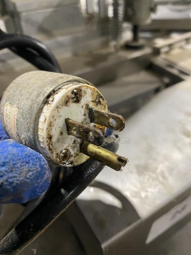 Patty O Matic Model 330A plug detail, showing a worn three-prong connection. Used condition, stainless steel machine in background.