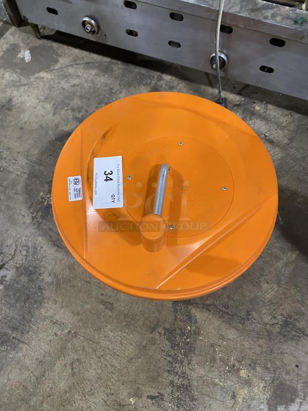 Orange commercial salad spinner with handle, in good condition. Auction tag indicates item number 34. Ideal for kitchen use.