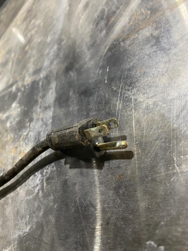 Close-up image of a power plug. Background shows scratched stainless steel surface. Auction item: Alto-Shaam oven.