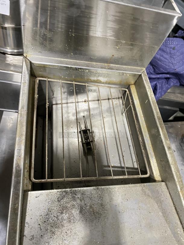 American Range commercial stainless steel gas fryer with grate, showing mild wear. Equipped with durable legs. Ideal for kitchens.